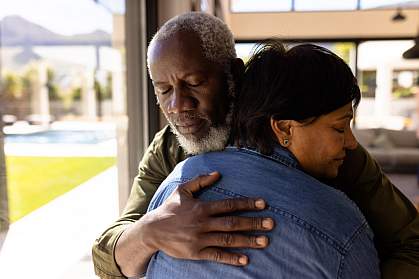 Senior man with his eyes closed embracing a woman while standing in nursing home. Senior man with his eyes closed embracing a woman while standing in nursing home.