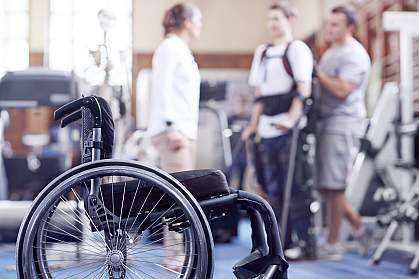Man receiving physical therapy with wheelchair in foreground. Man receiving physical therapy with wheelchair in foreground.