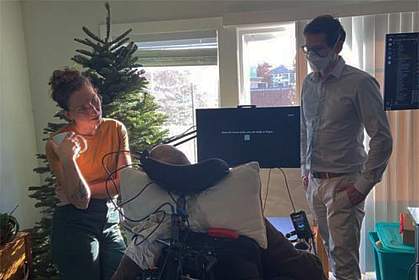 Photo of man in wheelchair in front of screen spelling out words. Photo of man in wheelchair in front of screen spelling out words.