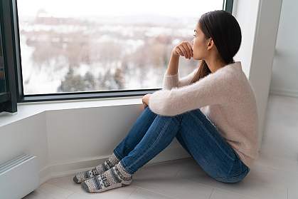 Young woman looking out the window in winter Young woman looking out the window in winter
