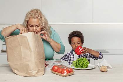 Mom and son taking healthy groceries out of a paper shopping bag. Mom and son taking healthy groceries out of a paper shopping bag.