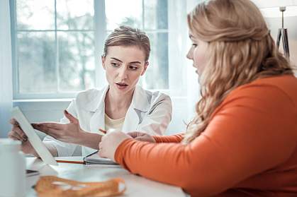 Teen with obesity speaking with a medical professional. Teen with obesity speaking with a medical professional.