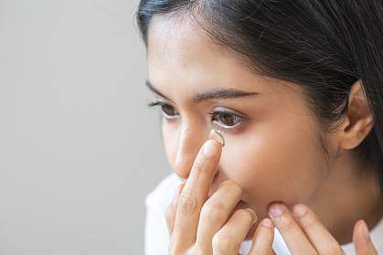 Teen putting a contact in her eye. Teen putting a contact in her eye.
