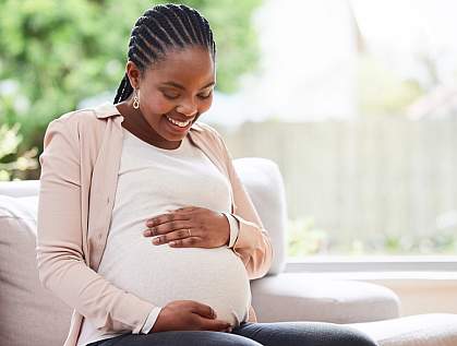 Pregnant woman on sofa smiling down at her belly. Pregnant woman on sofa smiling down at her belly.