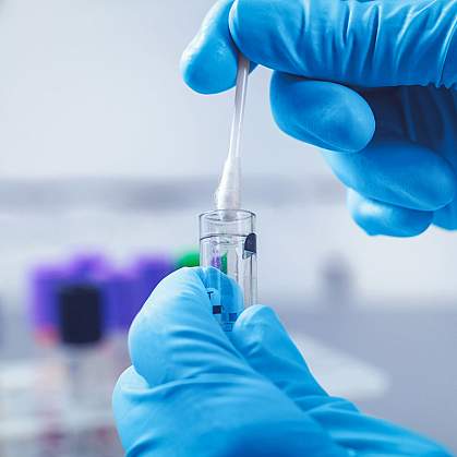 Close up of a swab being inserted into a test tube Close up of a swab being inserted into a test tube