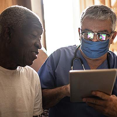 Doctor entering data into a tablet while talking with a patient Doctor entering data into a tablet while talking with a patient