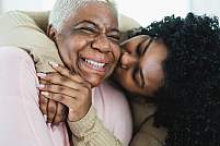 Adult daughter kissing smiling mother.