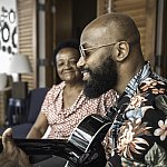 Image of a man playing a guitar and an older woman listening