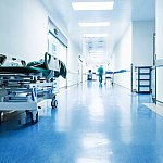 Medical worker blurred in the distance down an otherwise deserted hospital hallway.