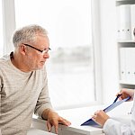 Doctor showing something on a clipboard to a senior man.