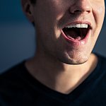 Close-up photo of the mouth of a man singing.